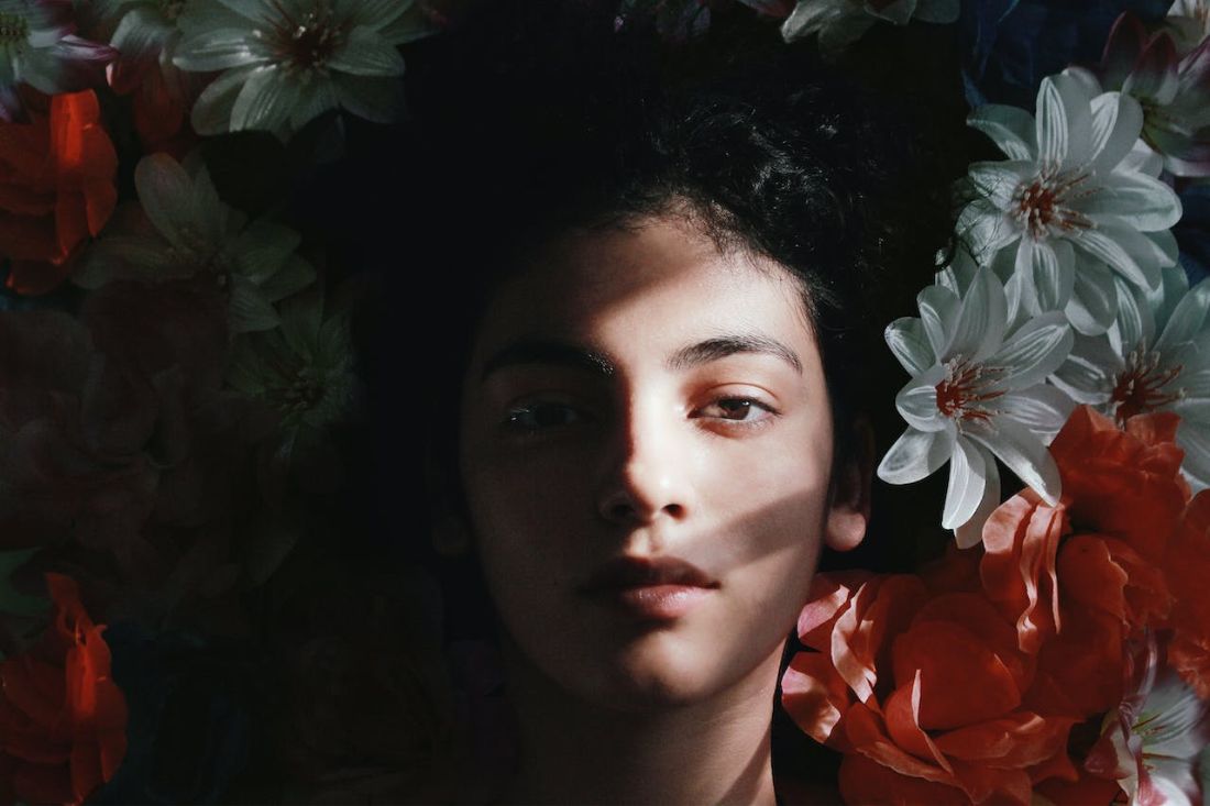 Gesetz der Anziehung oder loslassen (1) Ein Gesicht, halb im Schatten, halb im Licht, umgeben von roten und weißen Blumen – eine Metapher für die Suche nach Selbstliebe und innerer Freiheit. Erfahre mehr im Blogpost 'Vom Ego zur Selbstliebe: Der Weg zur Freiheit'.